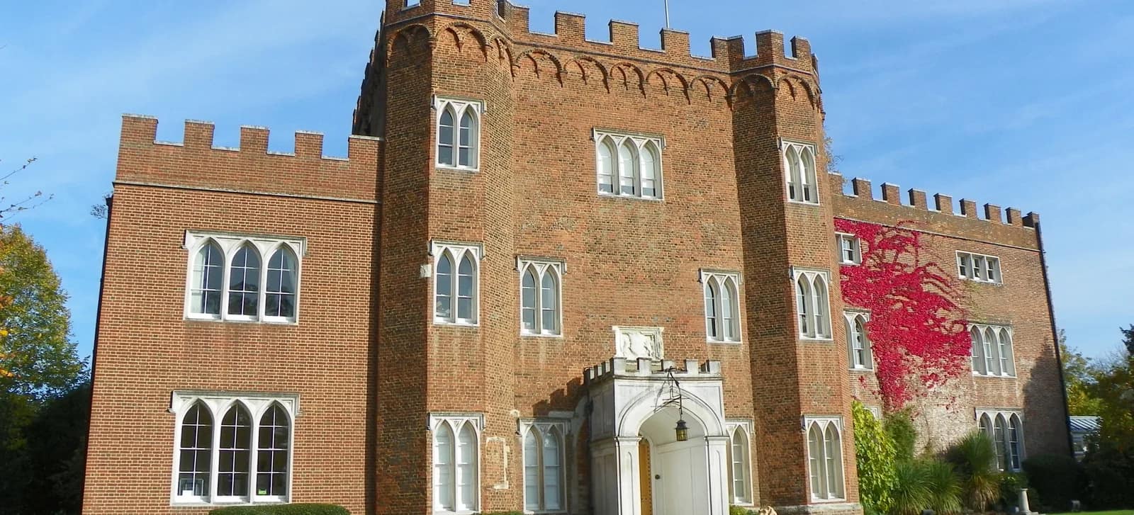 The brick gatehouse of Hertford Castle set in its lawned grounds