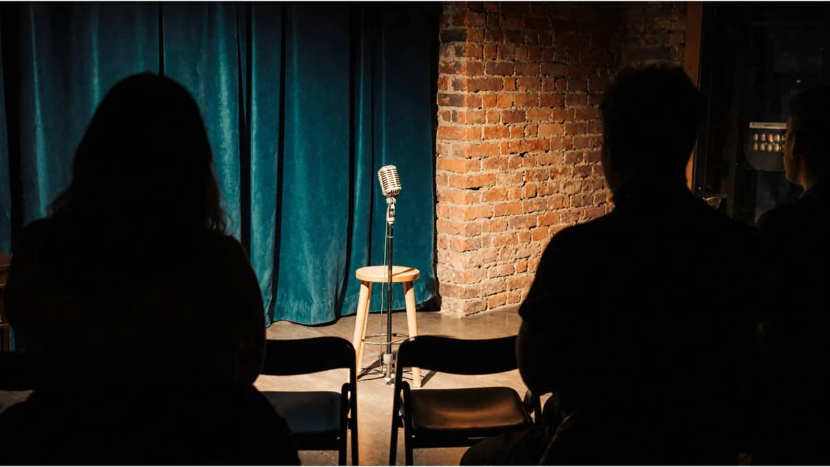 AI-generated illustration Audience silhouettes facing a small club stage with a microphone and stool — AI-generated illustration
